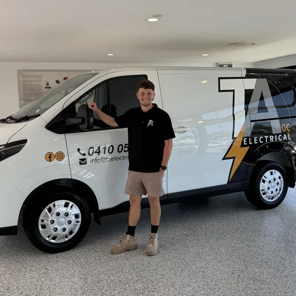 Sam standing beside the signwritten TA Electrical GC van, in a TA Electrical polo